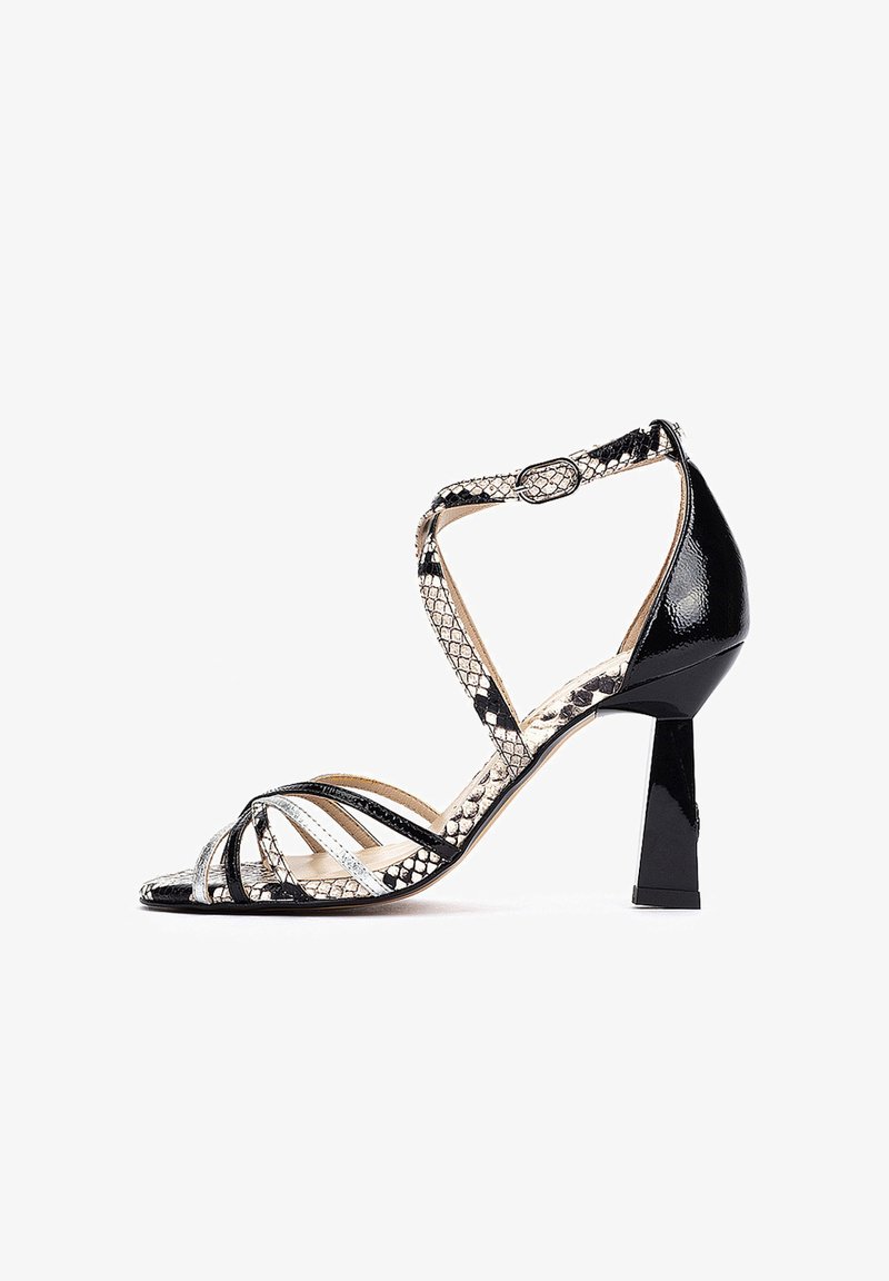 Sandale à talon haut noire et argentée avec un design en cuir verni et peau de serpent, présentant plusieurs brides et un talon carré géométrique.