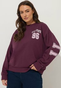 Felpa bordeaux realizzata in tessuto morbido, con stampe bianche "U.S. STATE" e "96" sul davanti e un particolare bianco sulla manica.