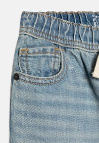 Lyseblå denimshorts med elastisk midje, en liten frontlomme og synlige s�ømdetaljer på kanten og lommene.