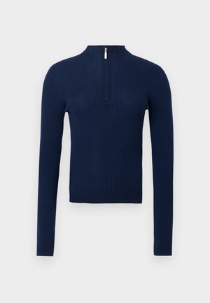 Tumesinist värvi soonikuga kampsun kõrge krae ja eespool pooleldi tõmblukuga. Pika varrukaga, tekstuurse kangaga ja keha järgiva lõikega.