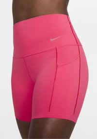 Sportowe szorty z wysokim stanem w intensywnym różowym kolorze, wykonane z gładkiego, elastycznego materiału. Cechy to płaskie szwy i małe logo w pobliżu pasa.