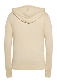 Beige kapucnis pulóver, hosszú ujjak, puha kötött anyag, bordás mandzsetta és szegély. Jellemzője egy hátulról nézett középső varrás és hozzákapcsolt kapucni.
