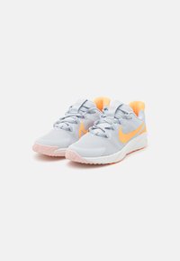 Baskets de sport gris clair avec des accents orange, tige texturée, bout renforcé et semelle en caoutchouc rose. Lacets ajustables et col rembourré.
