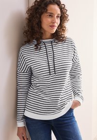 Svart- och vitrandig sweatshirt med huva, med dragsko och ribbade muddar, matchad med blåjeans. Texturerad tyg.