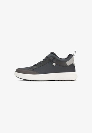 Scarpa sportiva grigia e nera con parte superiore testurizzata, chiusura con lacci e suola bianca. Presenta un occhiello sul tallone e un design minimalista.