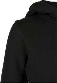 Sudadera negra con un tejido texturizado y suave, cuello redondeado y capucha de dos capas. Detalle de costura visible en los hombros.