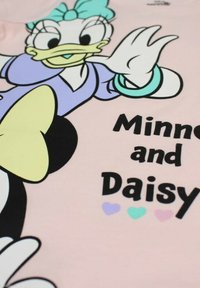 T-shirt en tissu rose présentant un personnage de canard dessiné en bande dessinée avec un nœud bleu, entouré du texte "Minnie et Daisy" en police noire audacieuse et des cœurs pastel.