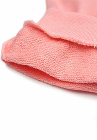 Licht koraalroze textiel met een zachte, textuurrijke oppervlakte, met een gevouwen rand en ribbeldetail aan de bovenkant.