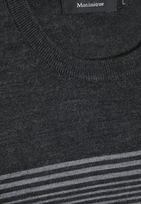 Pull en maille gris foncé avec col côtelé et rayures horizontales gris clair près du bas, montrant une étiquette de la marque Matinique à l’intérieur de l’encolure.