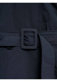 Granatowy pasek wykonany z materiału z kwadratową plastikową klamrą, o gładkiej fakturze i guzikiem w pobliżu miejsca zapinania.