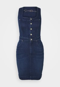 Denimdress med breda axelremmar, fyrkantig halsringning, knapplist fram, två sidofickor, mörkblå färg och figurnära design.