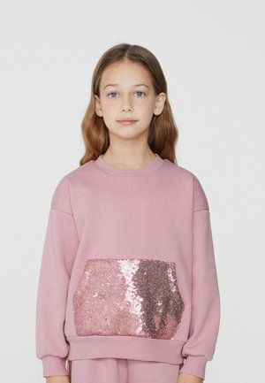Różowy sweatshirt wykonany z miękkiego materiału, z dużą kieszenią ozdobioną cekinami. Ma okrągły dekolt i luźne rękawy.