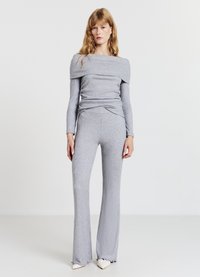 Graues, geripptes Strickoutfit bestehend aus einem langärmeligen Oberteil mit schulterfreiem Design und ausgestellten Hosen, mit rohen Säumen und weicher Textur.