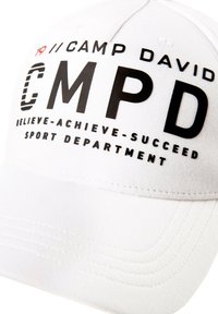 White cotton cap with a curved brim. Features black printed text: "CAMP DAVID CMPD BELIEVE-ACHIEVE-SUCCEED SPORT DEPARTMENT." Flat stitching.