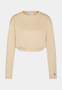 Beige langärmliger Crop-Sweater mit elastischem Saum und kleinem Champion-Logo am linken Ärmelbund.