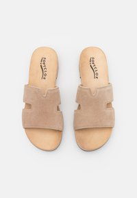 Beige suède slide sandalen met twee brede banden, voorzien van een snijd ontwerp en een lichte houten inlegzool. Zachte textuur en gevoerde basis.
