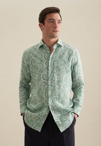 Camicetta verde a fantasia paisley con colletto button-down, maniche lunghe e intricati motivi bianchi. Realizzata in morbido tessuto testurizzato.