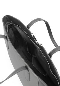 Graue Tragetasche mit glatter Außenfläche, doppelten Griffen und einem Reißverschluss. Das Innere verfügt über ein Wellenmuster-Futter und mehrere Taschen.