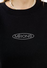 Felpa nera con colletto a coste e logo in strass argentati "MIRONS" in un motivo ovale sul petto.