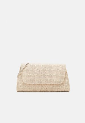 Pochette beige en tissu texturé avec rabat rectangulaire et bandoulière chaîne argentée sur fond uni.