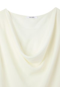 Top con collo a marsupio in crema chiaro, realizzato in tessuto morbido e leggero. Presenta una caduta rilassata e un'etichetta con il marchio "Terranova".