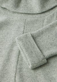 Ljust grått stickat tröjfabrikat med en mjuk, texturerad finish. Har en vikbar mudd och en lätt sömdetalj.