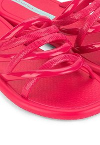 Infradito rosa con suola testurizzata, design della cinghia flessibile con dettagli intrecciati e finitura lucida.