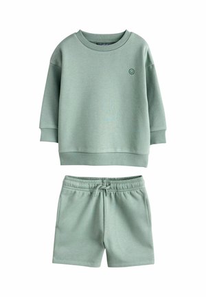 Jasnozielona bluza dziecięca z emblematem uśmiechniętej buźki oraz dopasowane szorty z elastyczną talią i sznurkiem, zestaw codzienny.