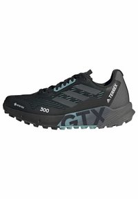 Scarpa da corsa nera con tomaia in mesh texturizzato, chiusura con lacci e suola in gomma spessa con accenti verdi e grigi. Mostra "GTX" e "300".
