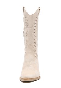 Bota de cowboy de ante beige con punta afilada, costuras decorativas, patrones cortados a láser, cremallera lateral y un tacón ligeramente elevado.