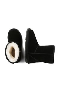 Black suede ankle boots with a soft white faux fur lining, flat rubber sole, and diagonal stitching details along the sides.