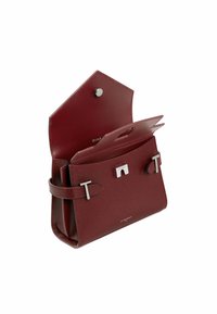 Sac à main en cuir texturé rouge avec une forme structurée, des accents en métal argenté et une fermeture à pression ; présente deux détails de bandoulière à l'avant.
