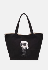 Black canvas tote bag featuring a cartoon character in sunglasses, with a cream interior and "KARL LAGERFELD" text at the bottom.