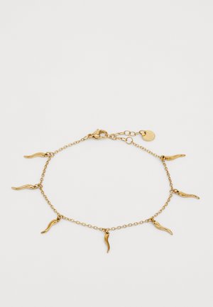 Zlatý náramok s predĺženými zakrivenými príveskami. Dizajn obsahuje zapínanie a nastaviteľnú dĺžku s malou logom značky.