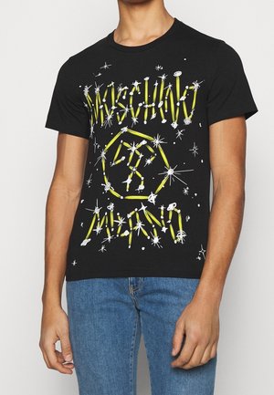 Musta puuvillainen T-paita, jossa on eloisat keltaiset ja valkoiset graafiset kuviot, tähdet ja viivakuviot sekä pyöreä pääntie.