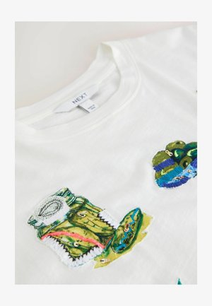 Weißes Baumwoll-T-Shirt mit farbenfrohen, bestickten Aufnähern von Essiggurken und Gläsern, mit Akzenten in Grün, Blau und Rot.