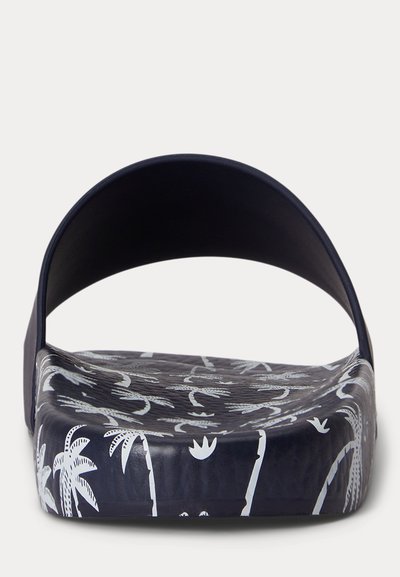 Granatowy klapek na płaskiej podeszwie z białymi wzorami tropikalnych palm i ptaków na wkładce i podeszwie, widziany z przodu.