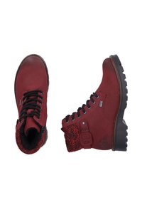 Bottes chelsea rouges avec un extérieur en daim lisse, bout rond, lacets noirs et un revers en tricot de laine. Équipées d'une semelle en caoutchouc épaisse et d'une fermeture éclair.