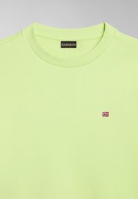 Sudadera verde clara con cuello redondo y puños de canalé. Cuenta con una pequeña bandera noruega bordada en la parte frontal. Textura suave.