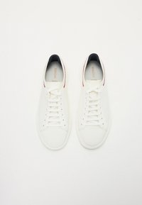 Sneakers bianchi in rete con lacci piatti, punta rotonda, fodera interna blu navy a contrasto e dettaglio rosso sul tallone. Superficie testurizzata per traspirabilità.