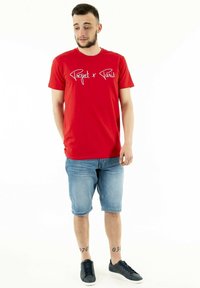 Red cotton t-shirt with "Project x Paris" white text on chest, paired with light blue denim shorts and dark sneakers. Casual fit.