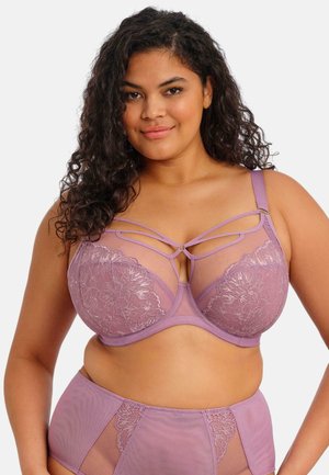 Lavendelfarbener Spitzen-BH mit durchscheinenden Netzdetails, Bügelunterstützung und dekorativem Trägerdesign. Passender hoch taillierter Slip inklusive.