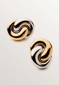 Los pendientes en espiral de oro y plata presentan un acabado suave y pulido con formas entrelazadas, destacando colores metálicos contrastantes y un diseño redondo.