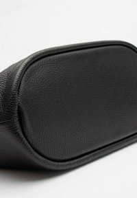 Borsa a tracolla in pelle nera con finitura testurizzata, bordi arrotondati e base piatta. Linee pulite e dettagli minimi esaltano il suo design.