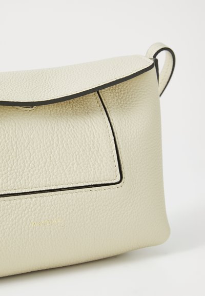 Krémová kožená taška s černým lemováním, vybavená klopnou a přední kapsou. Logo je vyraženo v dolní části přední strany.