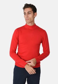 Maglione rosso a maglia con collo alto e maniche lunghe; presenta polsini e orlo a coste, realizzato in un tessuto morbido.