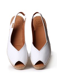 White leather espadrilles with open toe and slingback design. Natural fiber rope soles feature a woven texture. Smooth inner lining.