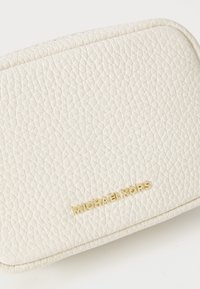 Bílý kožený sáček s texturovaným povrchem, s vyraženým zlatým logem "MICHAEL KORS" na přední straně a zakřiveným tvarem.