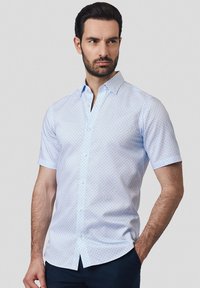 Koszula z krótkim rękawem w jasnoniebieskim kolorze w biały wzór w kropki. Posiada zapięcie na guziki z przodu oraz standardowy kołnierzyk.
