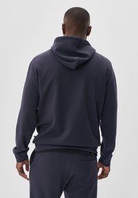 Felpa blu navy con cappuccio regolabile, vestibilità comoda, polsini a costine e tasca in vita. Tessuto liscio con una texture morbida.